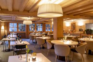 um restaurante com mesas, cadeiras e janelas em Hotel Edelweiss em Gerlos