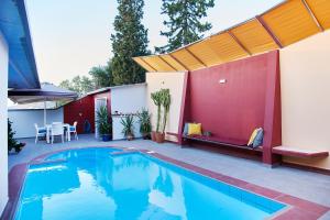 a swimming pool in a backyard with a red wall at The Bordeaux Door in Aegina Town