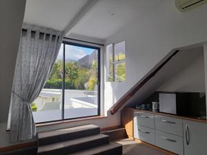 a living room with a large window and stairs at The Coach House in Franschhoek