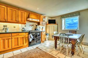 a kitchen with wooden cabinets and a table with chairs at Finest Retreats - Gag Barn in Ashbourne
