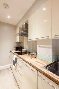 a kitchen with white cabinets and a wooden counter top at Beaufort Gardens Apartment in Knightsbridge in London