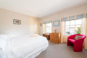 a bedroom with a white bed and a red chair at Stunning & spacious Georgian town house in St Neots town centre with parking in Saint Neots