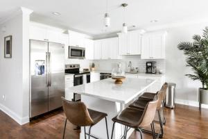 a white kitchen with a large white table and chairs at Liberty Garden in Savannah