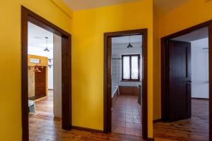 duas portas num quarto com uma parede amarela em Relais Castel d'Emilio – Casa ARANCIO em Cassero
