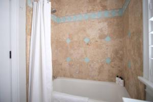 a bathroom with a tub and a shower curtain at Carriage House B at Hamilton in Savannah