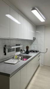 a kitchen with white cabinets and a sink at The Shim Anam 3rooms late check in-out in Seoul