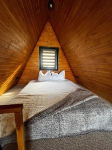 ein Schlafzimmer mit einem Bett in einer Holzhütte in der Unterkunft Rock Valley Cabins in Ibăneşti
