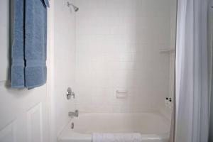 uma casa de banho branca com uma banheira e uma cortina de chuveiro branca em Carriage House A at Hamilton em Savannah