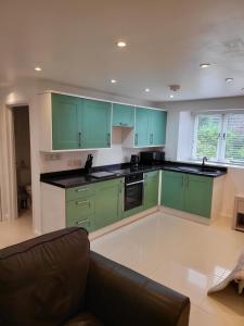 a kitchen with green cabinets and a couch at Beautiful One Bed Studio Flat - Dog Friendly in Bridgwater
