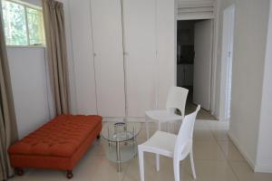 a living room with an orange couch and white chairs at Bryanston Elgin - Cottage 2 in Johannesburg