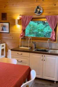 eine Küche mit einem Waschbecken, einem Tisch und einem Fenster in der Unterkunft Wood Cabin Hillside Retreat in Banja Luka