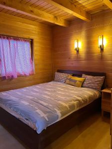 Bett in einem Holzzimmer mit Fenster in der Unterkunft Wood Cabin Hillside Retreat in Banja Luka