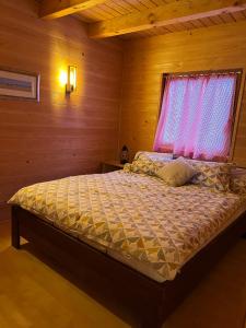 uma cama num quarto de madeira com uma janela em Wood Cabin Hillside Retreat em Banja Luka
