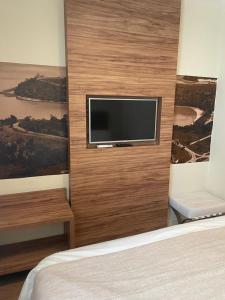 a bedroom with a flat screen tv on a wall at Quarto com acabamento superior no Design Hotel Linhares in Linhares