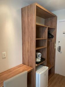 a kitchen with a wooden shelf with a white refrigerator at Quarto com acabamento superior no Design Hotel Linhares in Linhares