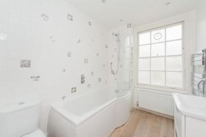 bagno bianco con vasca e finestra di Stylish 2 FLOOR 2BED house 1 MIN walk to Camden station! FREE PARKING! a Londra