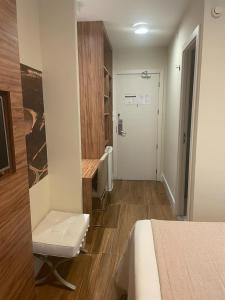 a room with a bed and a chair and a door at Quarto com acabamento superior no Design Hotel Linhares in Linhares