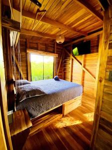 Cama en habitación de madera con ventana en Hoja Azul - Sustainable teak modern cabin in Hojancha, en Hojancha