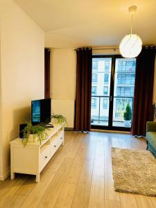 uma sala de estar com televisão e uma grande janela em Apartament blisko centrum Warszawy em Varsóvia