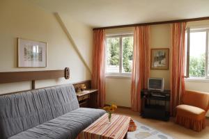 a bedroom with a couch and a chair and a television at Petersenhof in Millstatt