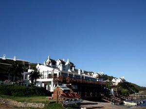 a large white building on a hill next to the water at Breede River Lodge in Witsand