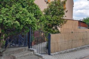 uma cerca preta com uma árvore ao lado de um edifício em Apartament, ogródek, przy Rynku! em Zielona Góra