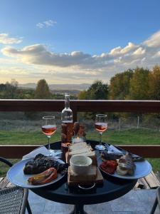 - une table avec deux verres de vin et de nourriture dans l'établissement Rock Valley Cabins, à Ibăneşti