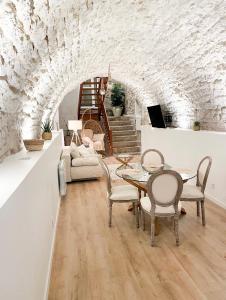 a living room with a table and chairs and a stone wall at La voute Doloise - Love room & spa in Dole