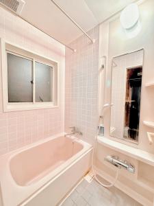 a white bathroom with a tub and a window at Moment Chalet Hakuba in Hakuba