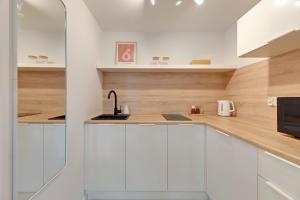 eine Küche mit weißen Schränken und Arbeitsflächen aus Holz in der Unterkunft Kamień by Grand Apartments in Gdynia