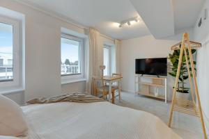 Schlafzimmer mit einem Bett, einem TV und Fenstern in der Unterkunft Kamień by Grand Apartments in Gdynia