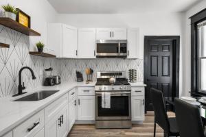 cocina con armarios blancos, fogones y fregadero en Modern City Luxury Home with Ample Parking in Charming Philly!, en Filadelfia