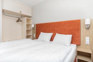 a bedroom with a bed with white sheets and an orange headboard at Rent like home - Bel Mare F324 in Międzyzdroje