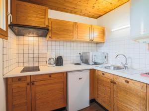 a kitchen with wooden cabinets and a white dishwasher at Studio Saint-Chaffrey , 1 pièce, 3 personnes - FR-1-762-11 in Saint-Chaffrey