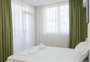 1 dormitorio con cama blanca y cortinas verdes en Brand New Modern 1BD Flat In Chayka with Parking, en Varna