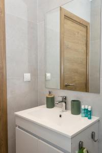 Baño blanco con lavabo y espejo en Brand New Modern 1BD Flat In Chayka with Parking, en Varna