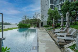 a swimming pool with tables and umbrellas next to a building at Cassia Residences 1 in Bang Tao Beach