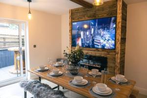 a dining room with a wooden table and a tv at 4 bedroom - Sleep 9 home in Cheadle Staffordshire - Alton towers Polar Express Dimmingsdale Peak District Trentham Gardens Water World in Cheadle