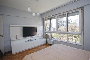 Habitación blanca con TV y 2 ventanas en Stylish 3 BR Family Apt in Palermo en Buenos Aires