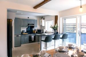 a kitchen with blue cabinets and a island with bar stools at 4 bedroom - Sleep 9 home in Cheadle Staffordshire - Alton towers Dimmingsdale Peak District Trentham Gardens Water World in Cheadle