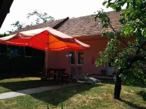 a red umbrella and a table and chairs in front of a house at Chata Sovička Podhájska in Podhájska