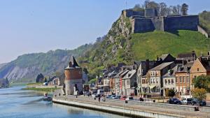 a town next to a river with a castle on a hill at Charmant T2 centre ville in Givet