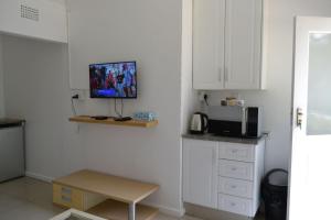 Il comprend une cuisine avec des placards blancs et une télévision murale. dans l'établissement Bryanston Elgin - Cottage 4, à Johannesbourg