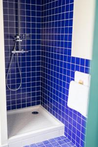 ナントにあるLe Lieu Ditの青いタイル張りのバスルーム(シャワー、バスタブ付)