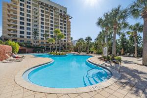 a swimming pool with palm trees and a building at Luau at Sandestin Tower I & II in Destin
