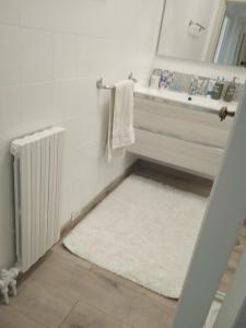 ein Badezimmer mit einem weißen Teppich, einem Waschbecken und einem Spiegel in der Unterkunft Sea Max Bogliasco in San Bernardo