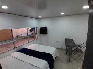 a bedroom with a bed and a desk and a window at Apartamento Grupal, Chapinero in Bogotá