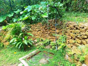 un jardín con una pared de piedra y una fuente de agua en The Moon House, en Weligama