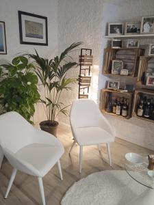 ein Wohnzimmer mit zwei weißen Stühlen und einer Pflanze in der Unterkunft Sea Max Bogliasco in San Bernardo