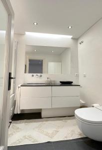 a white bathroom with a sink and a toilet at Groovy Caparica Gem with Large Sunny Terrace in Costa da Caparica